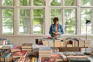 Lonely woman customer reading a book in old bookshop