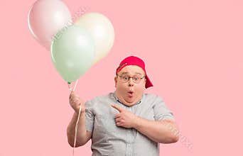 Surprised animator opening mouth widely, pointing at air balloons he holds.