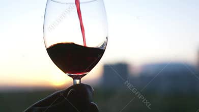 Puring alcoholic drink into the glass. Action. Close up of pouring red wine into the elegant transparent glass on