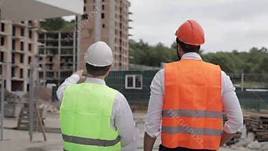 The builder and architect man are discussing the construction plan of the modern business center standing near