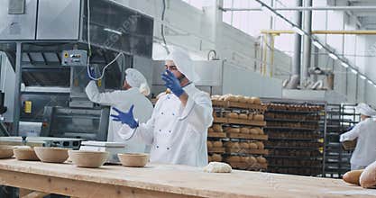In a bakery industry happy dancing baker have a fun time while preparing the dough for making a bread some workers