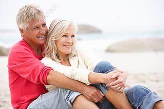 Senior Couple On Holiday Sitting On Winter Beach
