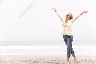 Senior Woman With Arms Outstretched On Beach