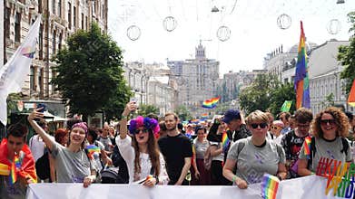Happy gay people with LGBT symbolism holding banner and taking selfie photos