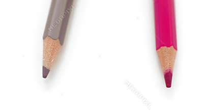 Extreme close-up, view from above, colored pencils rotating around on the white table