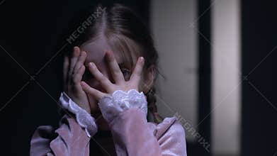 Frightened little girl closing face with palms, afraid of ghosts phobia concept