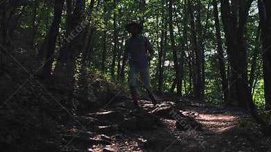 Close-up of the foot in the boot. A man hiker runs along the path in the summer forest. Hiker hiking in forest at sunset
