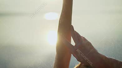 Beautiful young woman at sunrise in the water. She leads a healthy lifestyle. Large hands on the background of the dawn