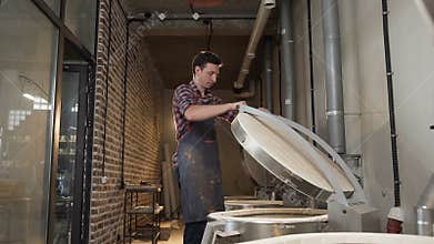 Caucasian man closing oven for firing ceramics pots.