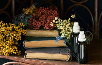 Bunches of dried wild herbs around old pharmaceutical books with recipes of alternative medicine