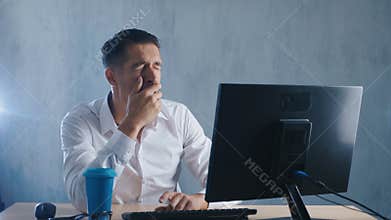 Tired businessman works at the computer. Boredom in the office. Unloved job.