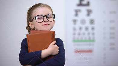 Bookworm kid in glasses hugging books, poor vision after reading too much