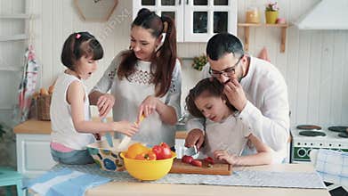 Happy family preparing food on kitchen, cutting vegetables, slow motion