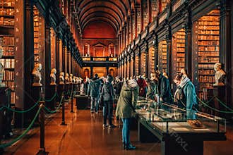 People visiting famous The Long Room in Old Library in Trinity College Dublin, Ireland.