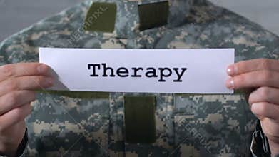 Therapy written on paper in hands of male soldier, help to war veterans