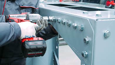 Tightening bolts on metal surface of industrial machine. Using screwdriver