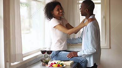 Happy african romantic young couple having fun embracing in kitchen