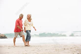 Senior Couple On Holiday Running Along Beach