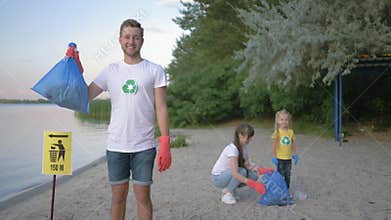 Environmental protection, portrait of happy volunteer male in rubber gloves with garbage bag near pointer sign on