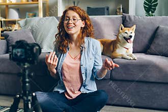 Beautiful blogger and cute dog recording video using camera at home talking