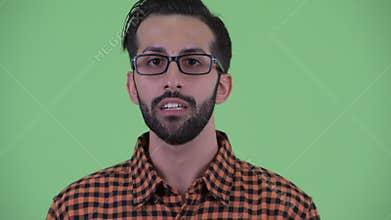 Face of happy young bearded Persian hipster man talking