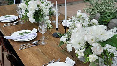 Decorating tables with bouquets of fresh flowers with candles and decor for a wedding or a party for a family feast.