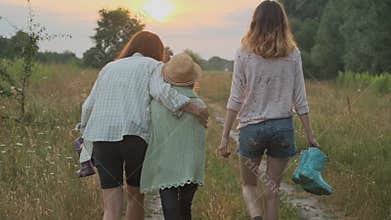 Family mother and children two daughters walking together along country road, back view