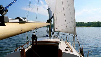 Sailing boat with white sails on the river.