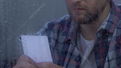Unhappy middle-aged man looking at family photo, suffering breakup, divorce