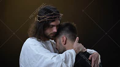 Savior in crown of thrones hugging desperate male, religious peace, forgiveness