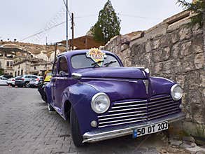 Goreme, Turkey - October 2019. Purple old time car parked on the paving street of the Cappadocia