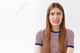 Girl feeling scared of consequences, look embarrassed and nervous, cringe face and clench teeth, frowning bothered