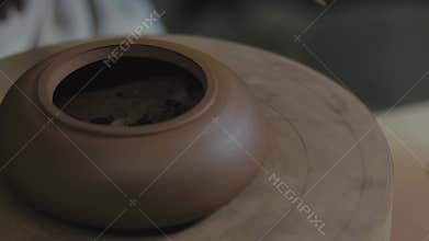 The master potter processes the teapot from Yixing clay with a metal spatula on a wooden shaft. Handmade clay teapot for tea