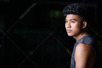 Profile view of young Asian man thinking at night outdoors
