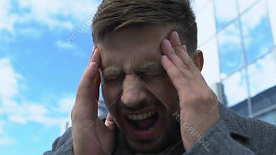 Tired business man having sharp pain attack outdoors, headache caused by stress