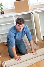 Handsome man rolling a carpet out