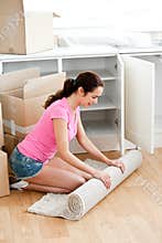 Joyful woman rolling a carpet out