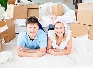 Joyful couple lying on floor after unpacking boxes