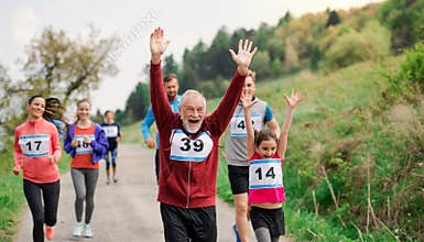 Large group of multi generation people running a race competition in nature.