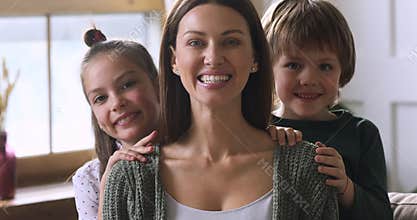 Cute children embracing mom from behind, family portrait