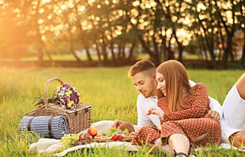 Happy young couple having picnic with tasty snacks