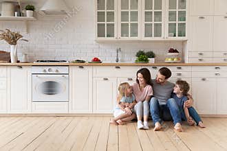 Happy family with children sitting on floor in modern kitchen