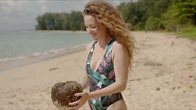 Puzzled female shaking coconut on beach