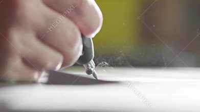 Macro of worker's hand is sandblasting writing on dark surface of granite block