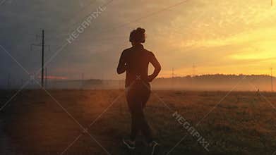 Sporty female jogger is running and training outside at the nature. Athletic woman is running during sunset time