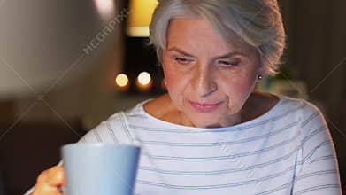 Senior woman with laptop drinking coffee at home