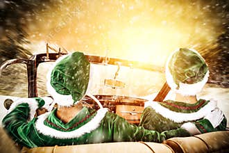 Two Elves in a car driving to deliver some christmas presents on a sunny winter day. Christmas decor on gold red background.