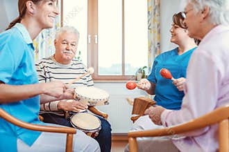 Seniors in nursing home making music with rhythm instruments