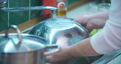 Woman washing dishes in sink in kitchen