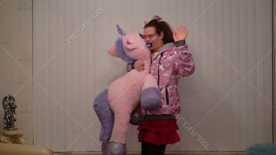 Funny adult person walking by with a stuffed unicorn and waving, LGBT diversity, Age regression and infantile behavior, Autism and